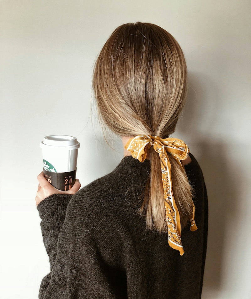 girl holding coffee with her hair in a ponytail